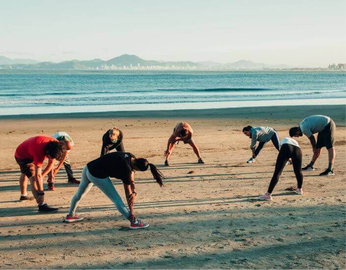 Atividade de alongamento na praia, ao amanhecer